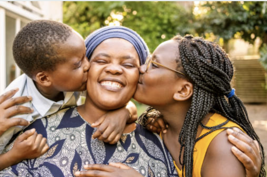 A mother greeted by her children at the school gate
